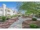 An exterior view featuring well-maintained grounds with lush trees and manicured lawns in front of the condos at 701 Wheat Ridge Ln # 203, Las Vegas, NV 89145