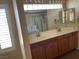 Bathroom vanity with double sinks, wooden cabinets, and well-lit mirrors at 7020 King Solomons Ct, Las Vegas, NV 89117