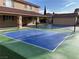 View of a spacious blue and green pickleball court adjacent to a tan home and a backyard shed at 7020 King Solomons Ct, Las Vegas, NV 89117