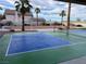 Pickleball court surrounded by landscaped grounds, palm trees, and exterior home view at 7020 King Solomons Ct, Las Vegas, NV 89117