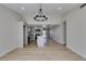 Open-concept space with wood-look floors, modern light fixture, flowing into a bright kitchen at 706 Greenway Rd, Henderson, NV 89002