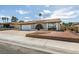 Exterior view of a one story home with desert landscaping, arched entryway, and two-car garage at 706 Greenway Rd, Henderson, NV 89002