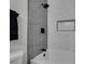 Tiled bathtub and shower with contrasting black hardware and built in niche at 706 Greenway Rd, Henderson, NV 89002