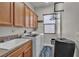 Laundry room with wood cabinets, a sink, and a modern washer and dryer set at 7228 Fern Meadow St, Las Vegas, NV 89149