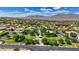 Wide aerial view showcases a meticulously landscaped community and a backdrop of majestic mountains under a blue, cloud-filled sky at 7289 Sea Anchor Ct, Las Vegas, NV 89131