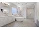 Bright bathroom features a standalone tub beneath a chandelier, along with dual sinks and a glass-enclosed shower at 7289 Sea Anchor Ct, Las Vegas, NV 89131