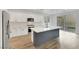 Well-lit kitchen features an island with seating, stainless steel appliances, and sliding glass doors to the backyard at 8043 Tank Loop St, Las Vegas, NV 89166