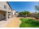 Well-maintained backyard with manicured lawn, desert landscaping, brick patio, and a cozy fire pit area at 8108 Artistic Heights Ct, Las Vegas, NV 89143