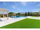 Backyard boasts lush green artificial turf, a modern pool with waterfalls, and mature trees at 9475 W Rosada Way, Las Vegas, NV 89149