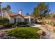 Picturesque backyard with artificial turf, mature landscaping, and a covered patio at 9524 Quail Ridge Dr, Las Vegas, NV 89134