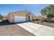 Single-story house featuring a two-car garage, desert landscaping, and wide driveway at 100 Eton St, Pahrump, NV 89048