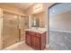Bright bathroom featuring a glass enclosed shower, wooden vanity, and neutral tile floors at 1044 Spanish Needle St, Henderson, NV 89002