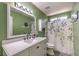 Bathroom with trendy green paint, white vanity, new lighting, and stylish shower curtain at 1073 Nordyke Ave, Henderson, NV 89015