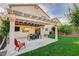 Backyard featuring a covered patio with an outdoor dining area, a grill, and a spacious grassy lawn at 10988 Salernes St, Las Vegas, NV 89141