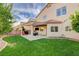 Backyard showcasing a covered patio, a dining area, well-maintained lawn, and beautiful landscaping at 10988 Salernes St, Las Vegas, NV 89141