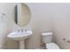 A cozy half bathroom that includes a pedestal sink, a round mirror, and a white toilet at 2373 Ozark Plateau Dr, Henderson, NV 89044