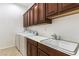 Functional laundry room features a sink with wooden cabinetry, and a modern washer and dryer at 2373 Ozark Plateau Dr, Henderson, NV 89044