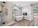 Elegant bathroom with a glass-enclosed shower, soaking tub, and contemporary fixtures under an arched window at 2409 Alpine Meadows Ave, Henderson, NV 89074