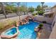 This backyard features a pool, hot tub, waterfall, and multiple palm trees at 2409 Alpine Meadows Ave, Henderson, NV 89074