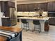Modern kitchen with dark cabinets, stainless steel appliances, and an island with seating at 242 Homeward Way, Henderson, NV 89011