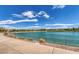 Scenic community pond with a walking path and lush landscaping under a blue sky at 242 Homeward Way, Henderson, NV 89011