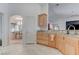 Open kitchen with light wood cabinets, stone countertops, tile flooring, and an arched entrance to the dining room at 2780 Avenue Of The Stars, Pahrump, NV 89060