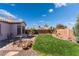 Charming backyard featuring a well-kept lawn, stone accents, mature landscaping, and an inviting outdoor seating area at 420 Aloha Dr, Henderson, NV 89015