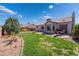 This backyard is meticulously landscaped with lush green grass, mature shade trees, patio, and drought-tolerant shrubs at 420 Aloha Dr, Henderson, NV 89015