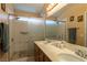 Bathroom features a double sink vanity, and a walk-in shower with tile surround and glass door at 6242 Halehaven Dr, Las Vegas, NV 89110