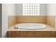 Bathroom featuring a large soaking tub surrounded by neutral-colored tile and block glass window at 7119 Wolf Rivers Ave, Las Vegas, NV 89131