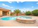 Inviting backyard pool and spa with a stone surround and a lush palm tree, creating a private oasis at 7119 Wolf Rivers Ave, Las Vegas, NV 89131