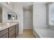 Bright bathroom featuring double sinks, granite counters, vanity, and a separate soaking tub at 9035 Drummer Bay Ave, Las Vegas, NV 89149