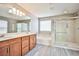 Bathroom with double sinks, soaking tub, glass shower, and wood-look flooring at 9271 Martel Ave, Las Vegas, NV 89148