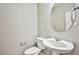 Half bathroom with modern toilet, pedestal sink, round mirror, and brushed nickel fixtures at 9271 Martel Ave, Las Vegas, NV 89148