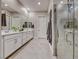 Bright primary bathroom featuring dual sinks with white cabinetry, tiled floors and a glass enclosed shower at 101 Mirage View Dr, Henderson, NV 89011