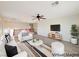 Virtual staged living room with white furniture, area rug, ceiling fan, and television at 10469 Mulvaney Cir, Las Vegas, NV 89141