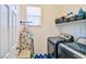 This laundry room has a gray washer and dryer with white walls and shelf storage at 10667 Olympic Pine Dr, Las Vegas, NV 89135