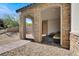 Covered front porch with stone arches, brick flooring, and outdoor seating area at 11856 Barona Mesa Ave, Las Vegas, NV 89138