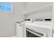 Laundry room featuring a front loading washer and dryer with storage shelves at 11856 Barona Mesa Ave, Las Vegas, NV 89138