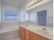 Well-lit bathroom featuring double sinks, a large soaking tub, and a window at 1424 Heartstring Ct, Henderson, NV 89002