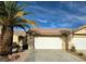 Inviting home exterior featuring a two-car garage complemented by a mature palm tree and desert landscaping at 2035 E Warm Springs Rd # 1017, Las Vegas, NV 89119