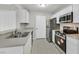Modern kitchen featuring stainless steel appliances, white cabinets, a double sink, and tile flooring at 230 Mission Newport Ln # 104, Las Vegas, NV 89107