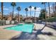 Community pool with turquoise water, palm trees, lounge chairs, and nearby residential buildings on a sunny day at 230 Mission Newport Ln # 104, Las Vegas, NV 89107