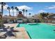 Community pool with turquoise water, palm trees, lounge chairs, and a community building on a sunny day at 230 Mission Newport Ln # 104, Las Vegas, NV 89107