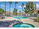 Community pool and jacuzzi with turquoise water, palm trees, lounge chairs, and nearby residential buildings on a sunny day at 230 Mission Newport Ln # 104, Las Vegas, NV 89107
