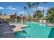 Community pool with turquoise water, palm trees, lounge chairs, and nearby residential buildings on a sunny day at 230 Mission Newport Ln # 104, Las Vegas, NV 89107