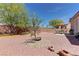 Red rock landscaping with a stone sitting area and a charming mature tree in the backyard at 2304 Willow Wren Dr, North Las Vegas, NV 89084