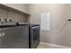 Functional laundry room with modern, matching washer and dryer and built-in storage shelves at 2367 Ridgeline Wash St, Las Vegas, NV 89138