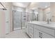 Luxurious bathroom with dual vanities, a glass-enclosed shower, and neutral tile flooring at 2367 Ridgeline Wash St, Las Vegas, NV 89138
