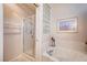 A bathroom featuring a glass enclosed shower, soaking tub, and a decorative glass block window at 2801 Byron Dr, Las Vegas, NV 89134